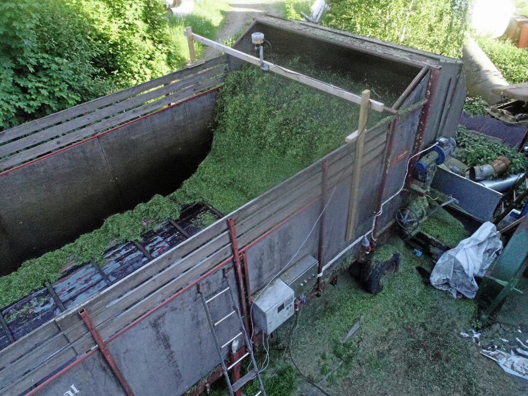 Nivåsensorn på plankan mäter gräsmängden på avlastarbordet och signalerar till en dator (PLC). Via en frekvensomvandlare justeras hur mycket grönmassa som ska portioneras ner på transportörbandet för att sedan kastas upp i tornsilon.